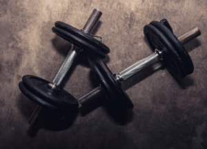 Dumbbells on a gym floor representing strength training, muscle building, resistance workouts, and fitness performance.