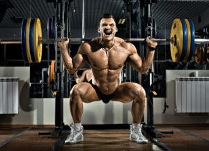 Muscular bodybuilder performing a heavy barbell squat with multiple weight plates during an intense leg workout. Strength athlete demonstrating lower-body power, quadriceps development, glute activation and overall muscle growth in a professional gym environment. Image representing bodybuilding, powerlifting, strength training, hypertrophy, muscle-building workouts, athletic performance, progressive overload and advanced resistance training techniques for maximum size and strength gains.
